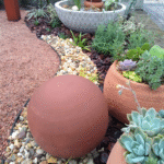 Jardim para quintal pequeno com fonte decorativa de vasos de cerâmica, suculentas em vasos rústicos, esfera de barro, pedras ornamentais e plantas verdes