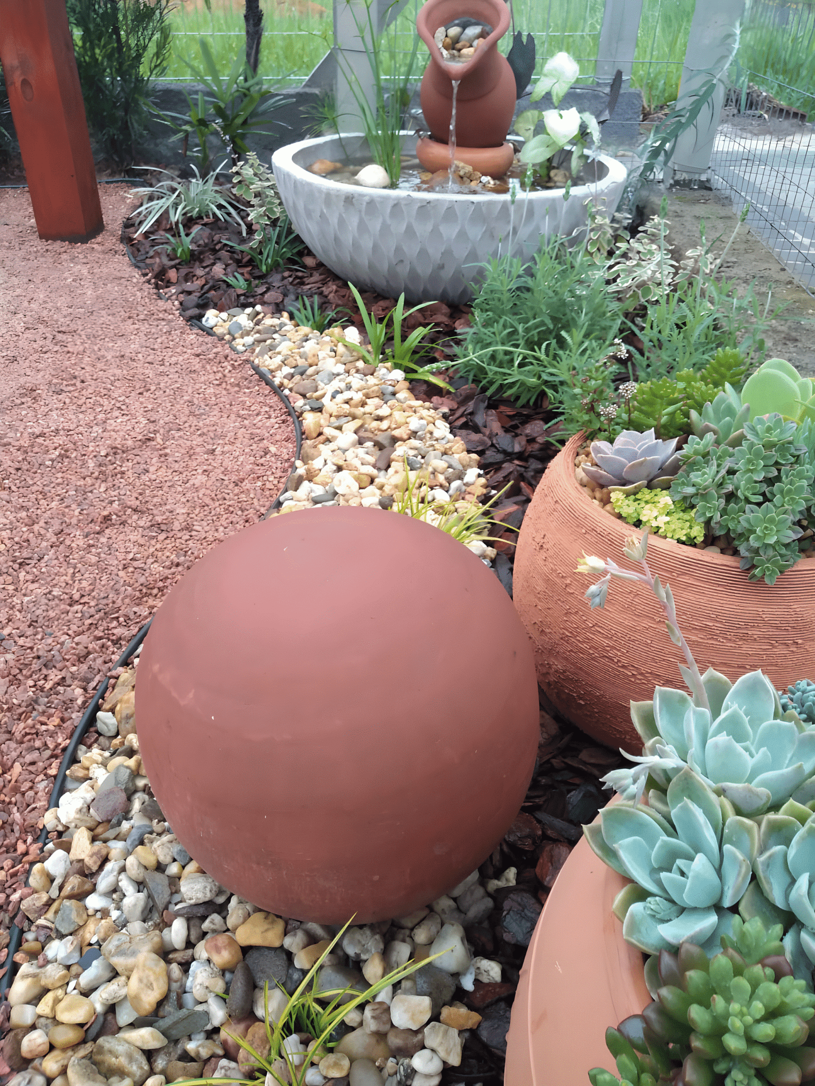 Jardim para quintal pequeno com fonte decorativa de vasos de cerâmica, suculentas em vasos rústicos, esfera de barro, pedras ornamentais e plantas verdes