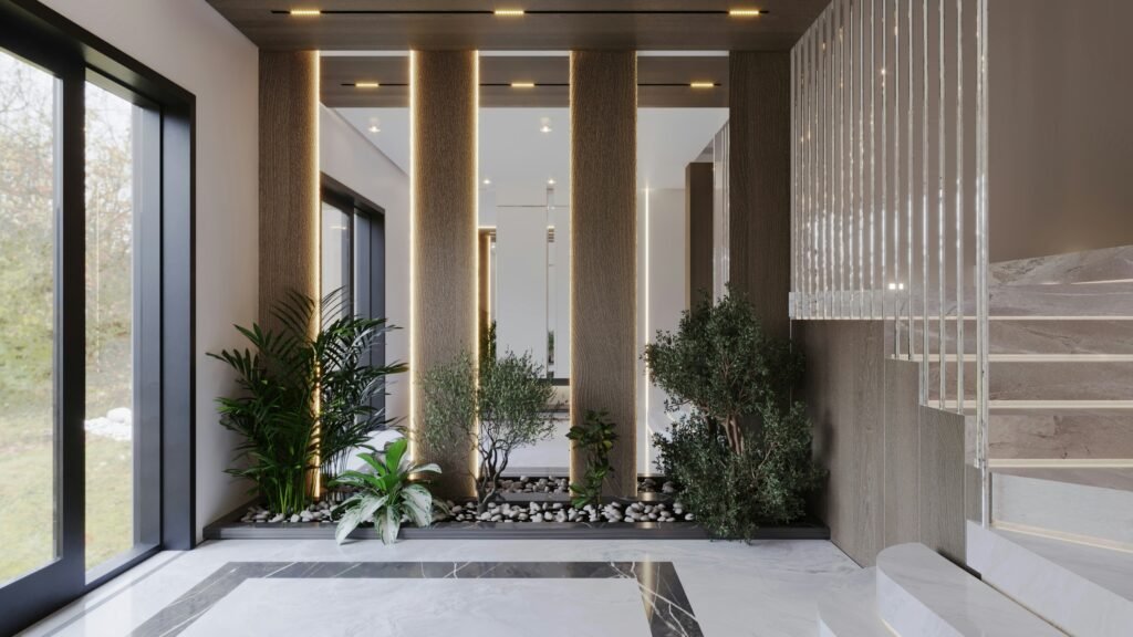 Jardim de inverno para sala moderna, com plantas verdes dispostas no chão entre colunas iluminadas, pedras brancas decorativas, piso de mármore e grandes janelas de vidro.