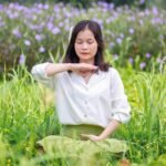 Jovem meditando em um campo florido como um jardim zen