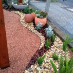 jardim para quintal pequeno com pedras decorativas e vasos.
