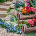 vasos rústicos de madeira com flores coloridas em jardim decorado com pedras e plantas ornamentais