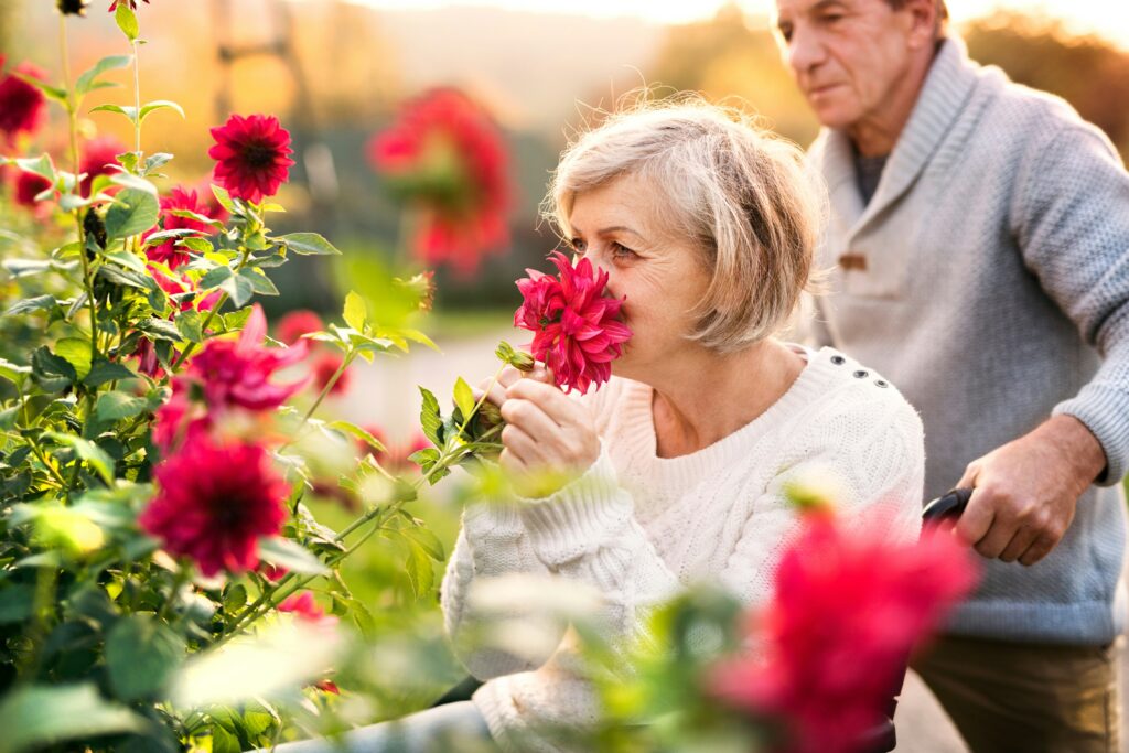 Mulher apreciando o perfume de flores em um jardim, simbolizando conexão e bem-estar