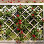 Jardim vertical com flores vermelhas e brancas em estrutura de madeira decorativa