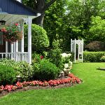 jardim residencial com gramado bem cuidado, flores coloridas, arbustos e decoração em frente a uma casa