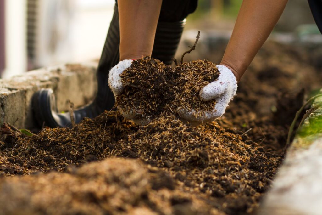 mãos com luvas brancas preparando o solo de horta com matéria orgânica e substrato