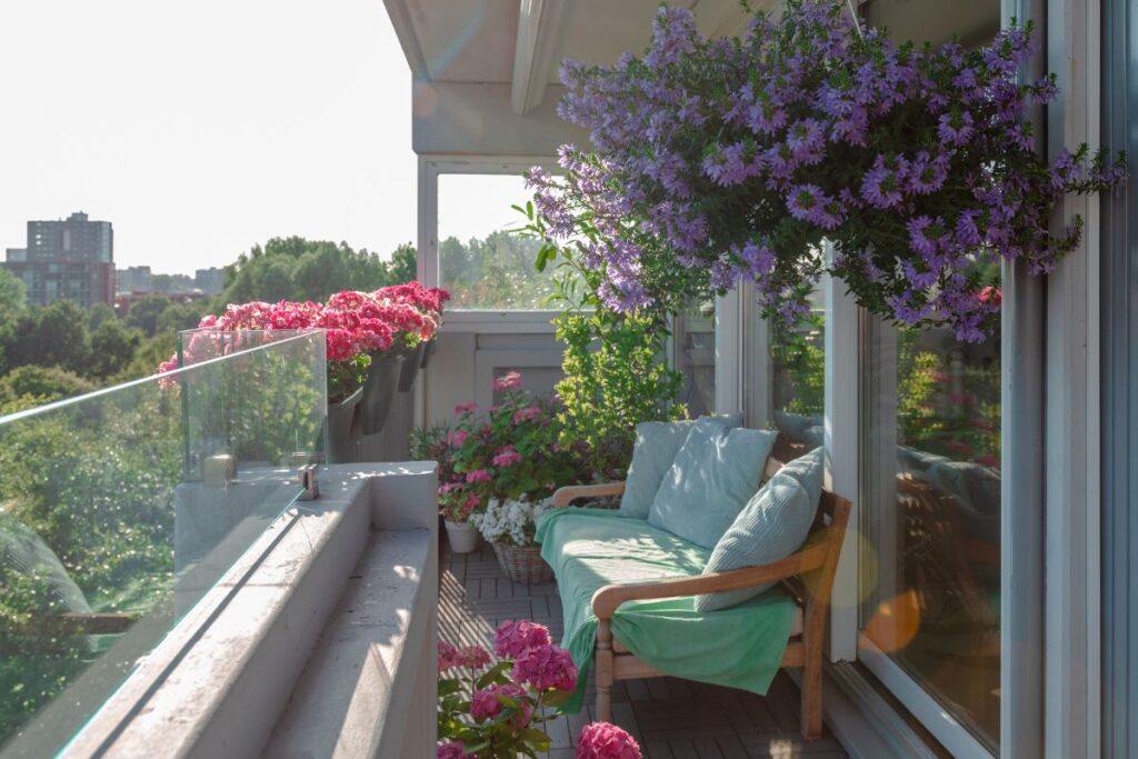 varanda pequena decorada com flores coloridas, plantas verdes e sofá aconchegante, integrando lazer e jardim em espaço reduzido