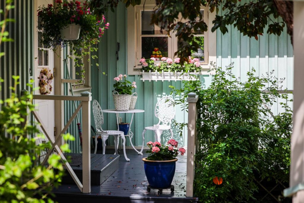 varanda decorada com plantas e flores em vasos, criando um espaço verde acolhedor e relaxante