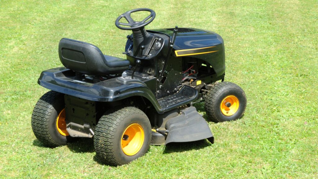 Cortador de grama trator em gramado verde, usado para manutenção de grandes áreas e jardinagem profissional.