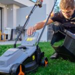 Homem usando cortador de grama com coletor em jardim residencial.