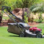 Cortador de grama com motor a gasolina sobre gramado, ilustrando a diferença entre motores 2 tempos e 4 tempos usados em diferentes tipos de cortadores de grama.
