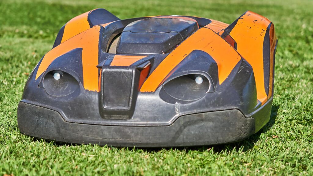 Cortador de grama robô em funcionamento sobre gramado verde, representando automação, tecnologia e eficiência no cuidado com o jardim.
