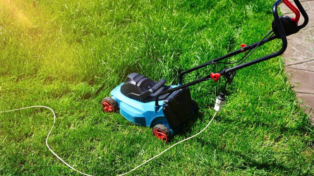 Cortador de grama elétrico com fio em funcionamento sobre gramado residencial, representando o uso prático e eficiente do cortador de grama para terrenos irregulares de pequeno porte e áreas planas.