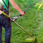 pessoa usando uma roçadeira para cortar a grama em um jardim bem cuidado