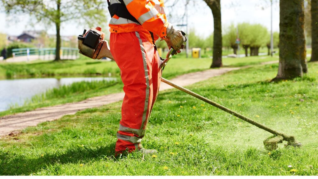 Profissional utilizando roçadeira em área verde após regulagem do carburador.