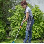 Mulher cuidando do jardim com ferramenta de corte, representando a escolha certa dos tipos de roçadeira