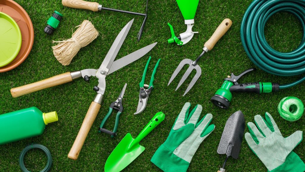 Kit de ferramentas de jardinagem para pequenos espaços e vasos, incluindo pás, tesouras de poda, borrifador e luvas sobre gramado artificial.