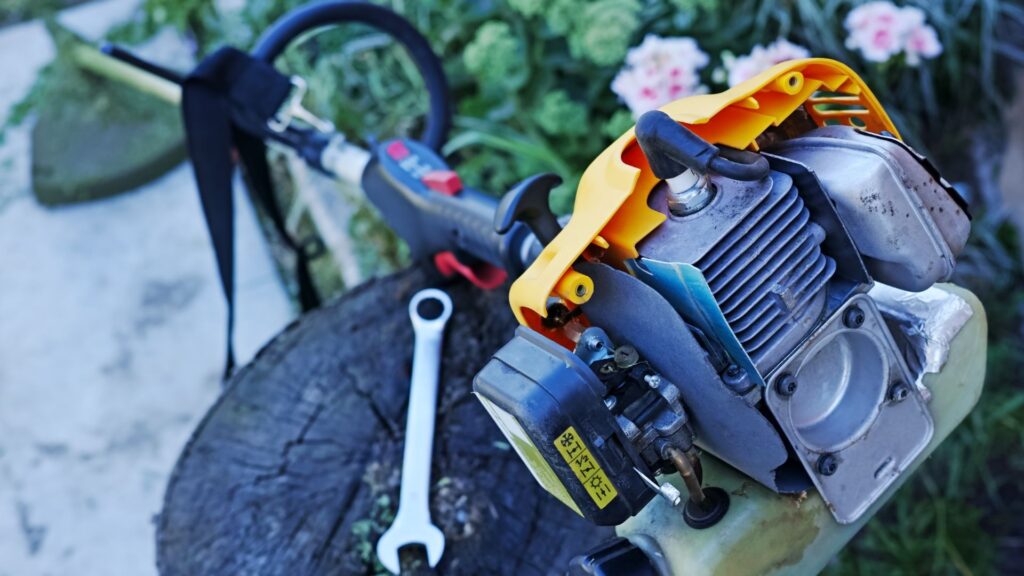 roçadeira a gasolina sobre um tronco durante manutenção, com ferramentas ao redor- manutenção de roçadeira