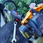 roçadeira a gasolina sobre um tronco durante manutenção, com ferramentas ao redor- manutenção de roçadeira