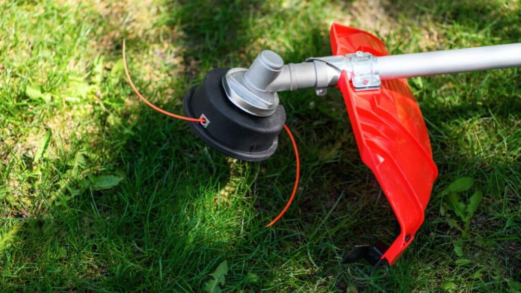 Roçadeira a gasolina realizando corte de grama em área de jardim