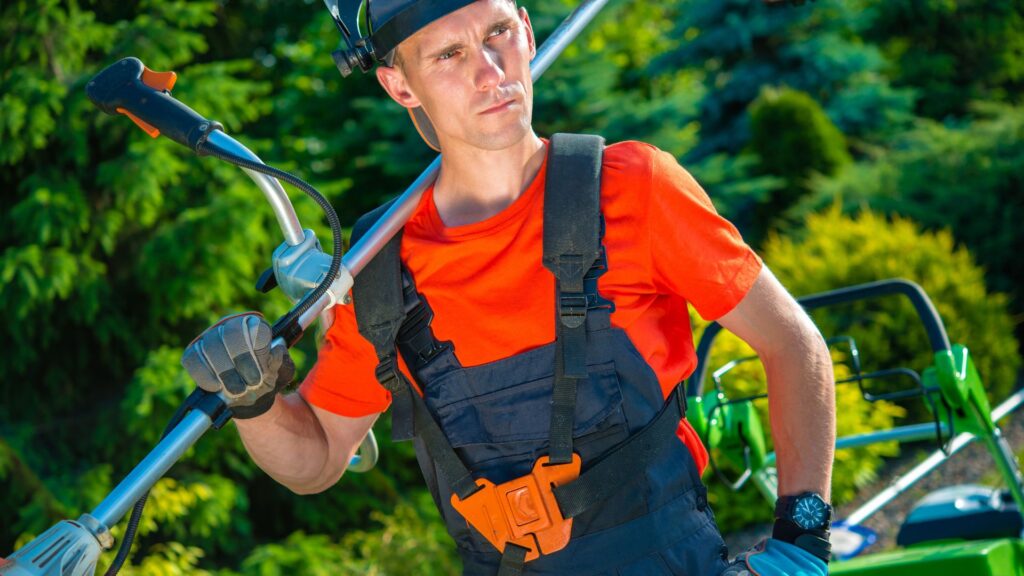 Operador de roçadeira usando EPI completo durante atividade ao ar livre, transmitindo seriedade e preparo.