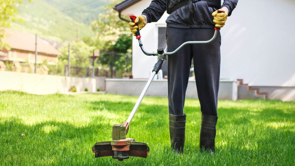 Homem utilizando roçadeira a gasolina em gramado residencial, mostrando praticidade e eficiência no corte da grama.