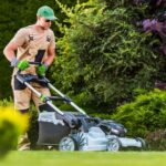 Homem utilizando um cortador de grama elétrico moderno em um jardim, representando os diferentes tipos de cortadores de grama.