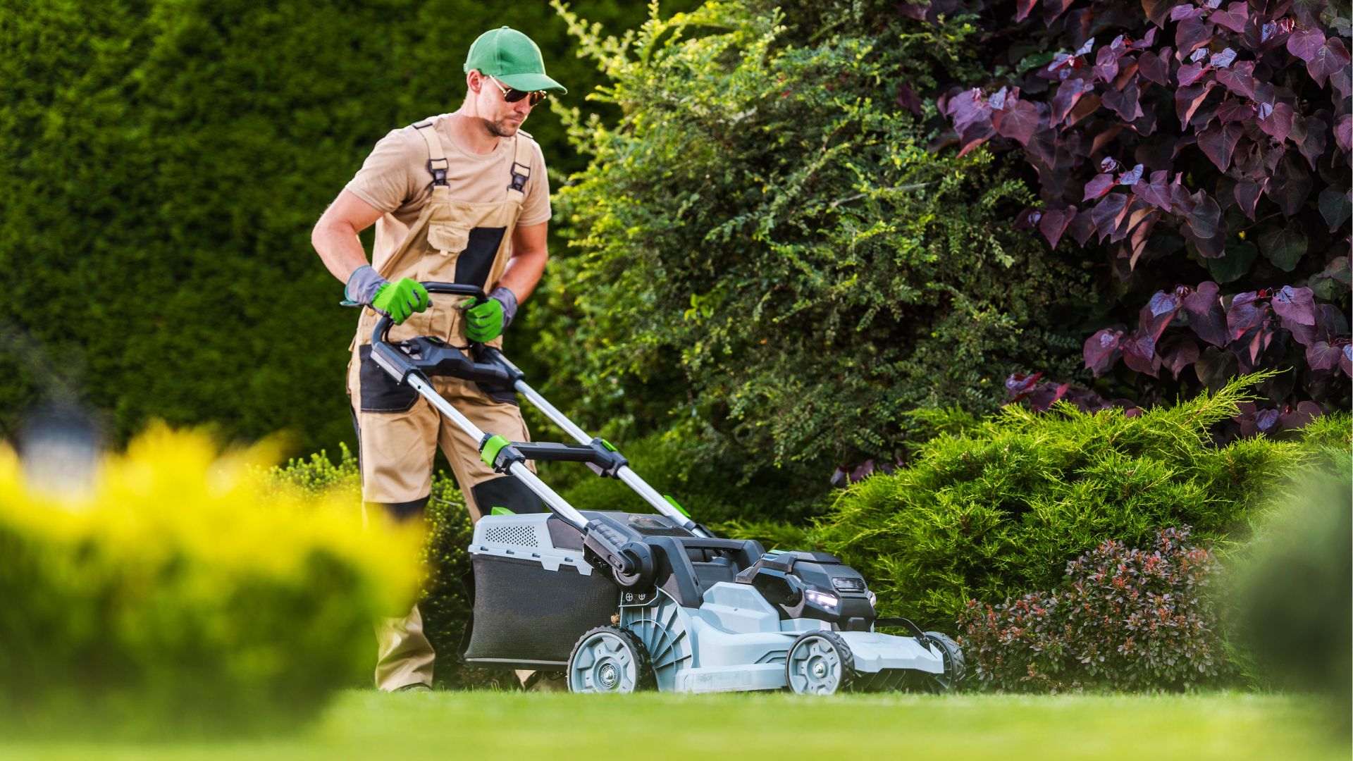 Homem utilizando um cortador de grama elétrico moderno em um jardim, representando os diferentes tipos de cortadores de grama.