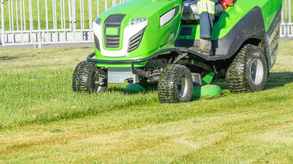 Trator cortador de grama em funcionamento sobre terreno amplo e inclinado, ilustrando a eficiência do cortador de grama para terrenos irregulares e de grandes dimensões.