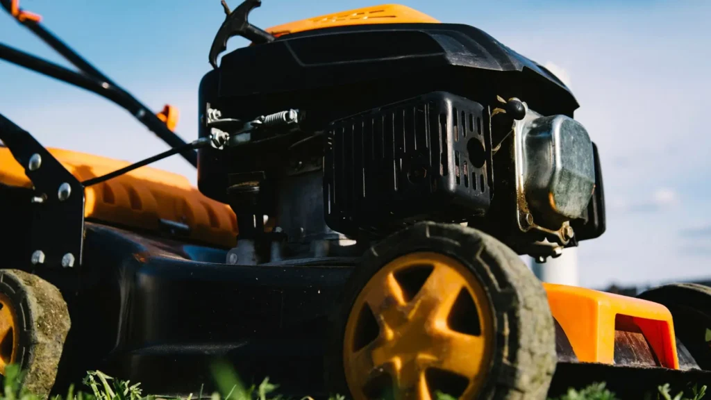 Cortador de grama moderno com motor quatro tempos em funcionamento, mostrando detalhes do motor e estrutura com rodas.