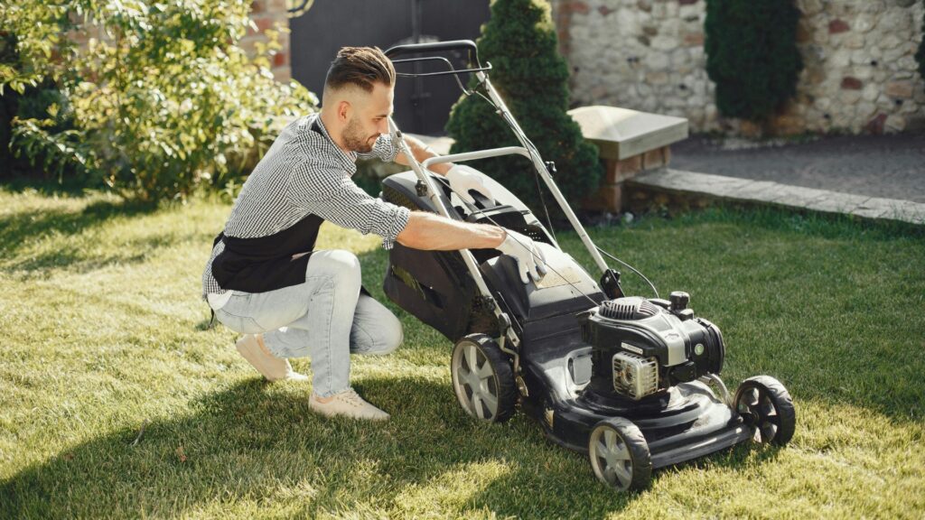homem ajustando cortador de grama a gasolina com tração durante o uso no jardim