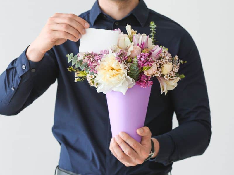 flores para o Dia da Mulher acompanhadas de cartão, representando cuidados e possíveis interpretações ao escolher a homenagem