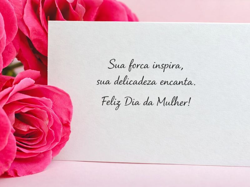 mensagem dia da mulher para amiga em cartão branco ao lado de rosas cor de rosa representando carinho e amizade