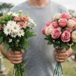 Pessoa segurando flores naturais ou artificiais em Finados, com sepulturas desfocadas ao fundo.